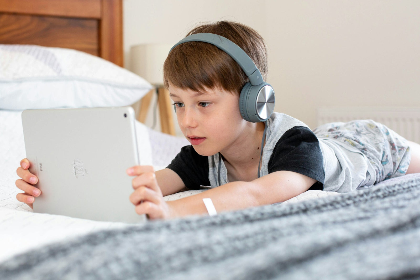 Niño usando una tablet en la cama
