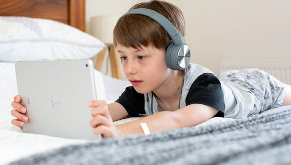 Niño usando una tablet en la cama