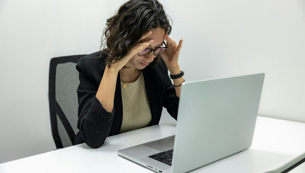 Mujer frotándose los ojos cansados delante del portátil